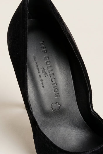 Close-up of a black velvet pump with a gold metal toe cap and a dark leather insole inside