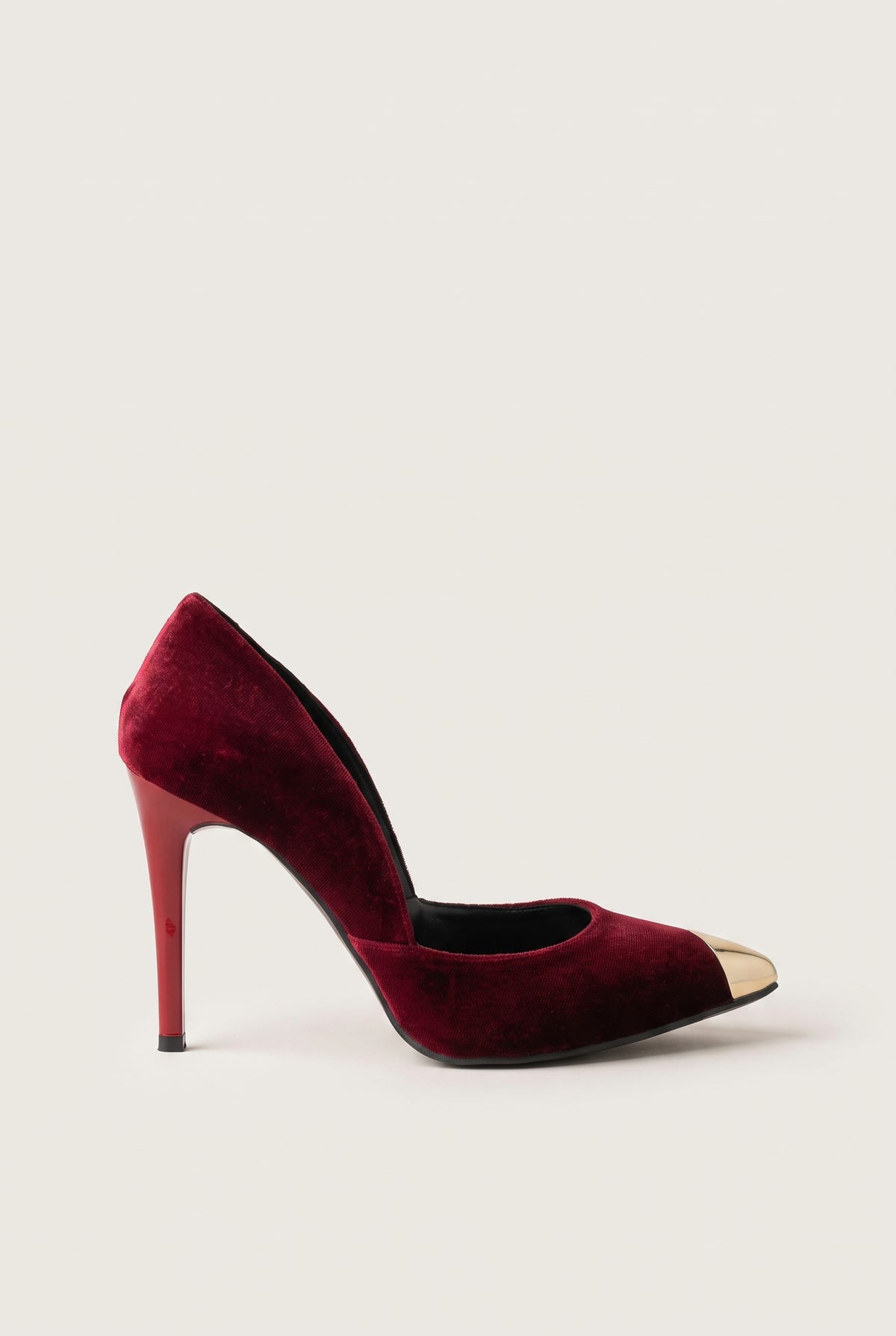 Side view of a bordeaux velvet pump with a cut-away side, a gold metal toe cap and a tall slim heel