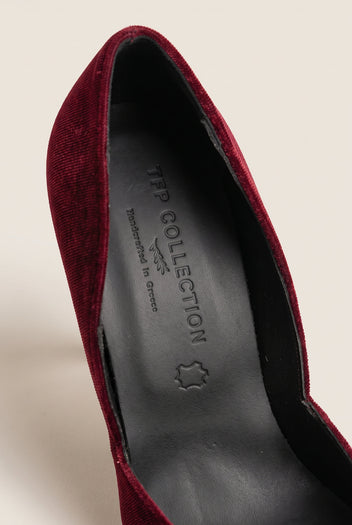 Close-up of bordeaux velvet upper curving along a dark leather insole inside the pump