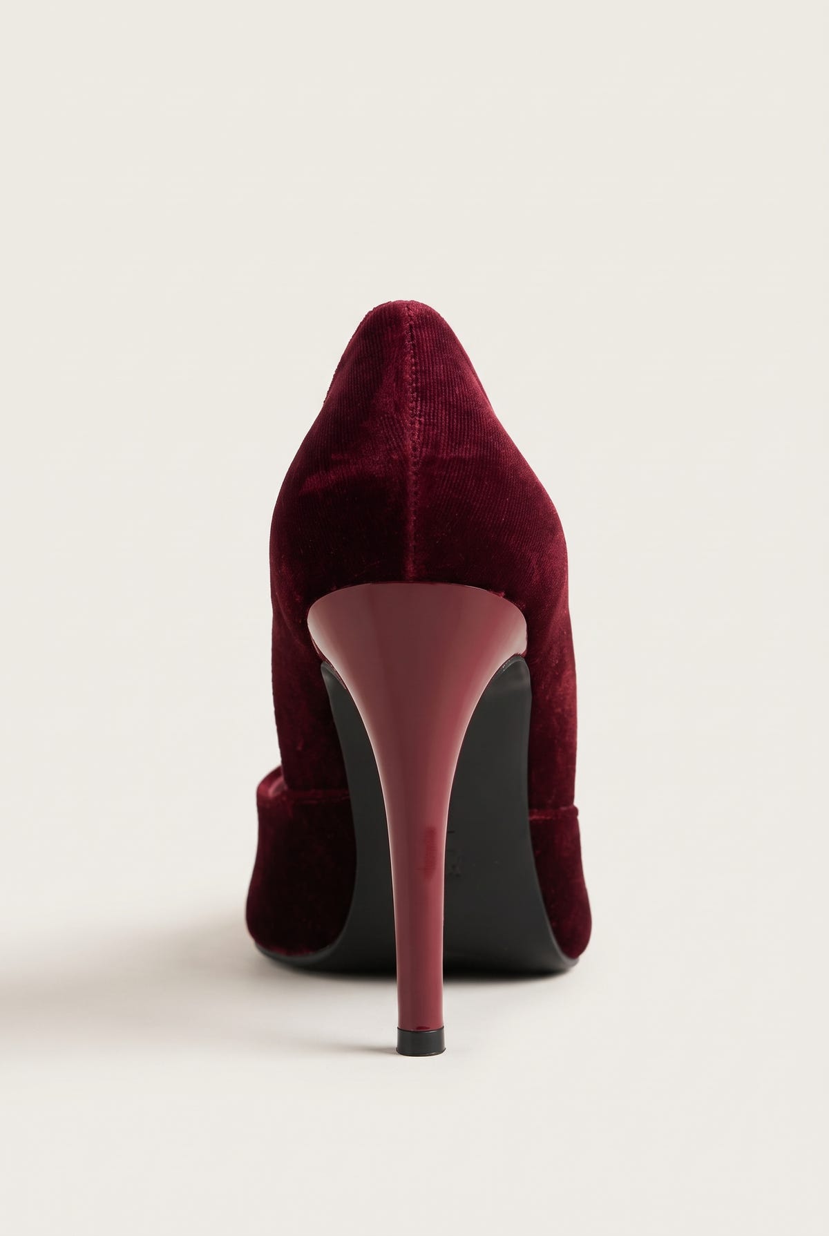 Back view of a bordeaux velvet pump with a tall slim heel in a matching bordeaux tone