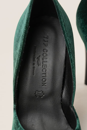 Close-up of a dark green velvet pump with the upper edge curving along a dark leather insole