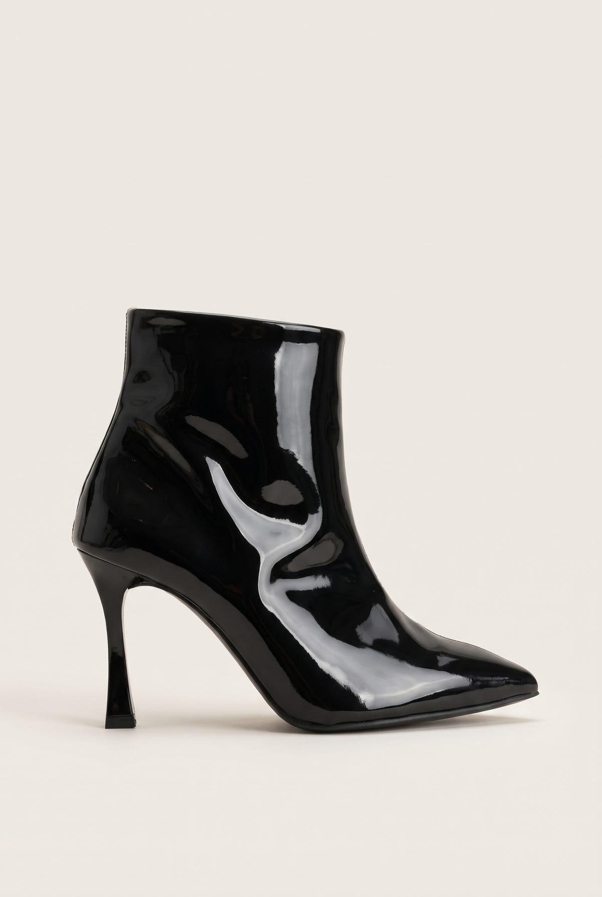 Black patent pointed toe ankle boot with slim stiletto heel in side view on a light surface