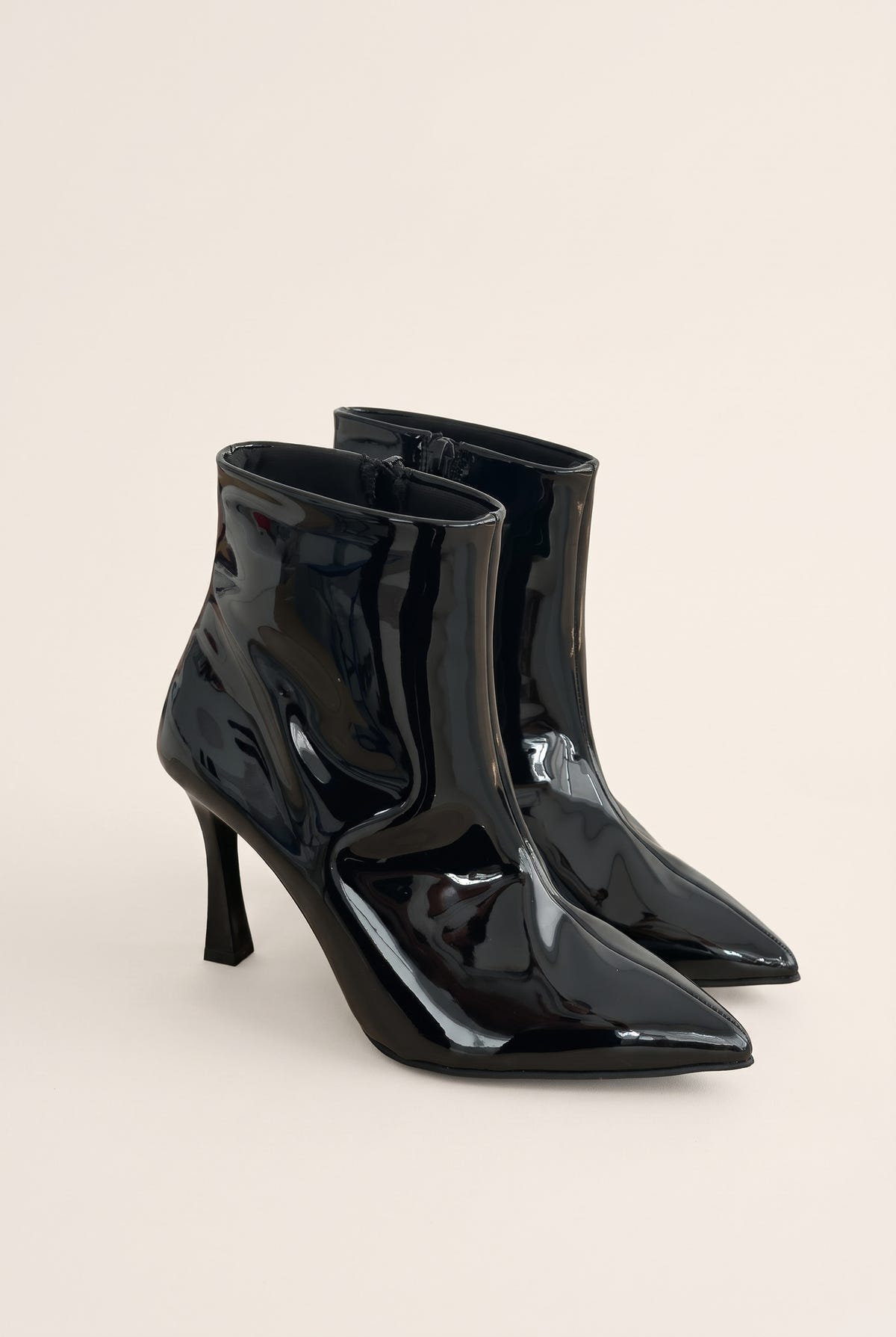 Pair of black patent pointed toe ankle boots with slim stiletto heels in angled front view