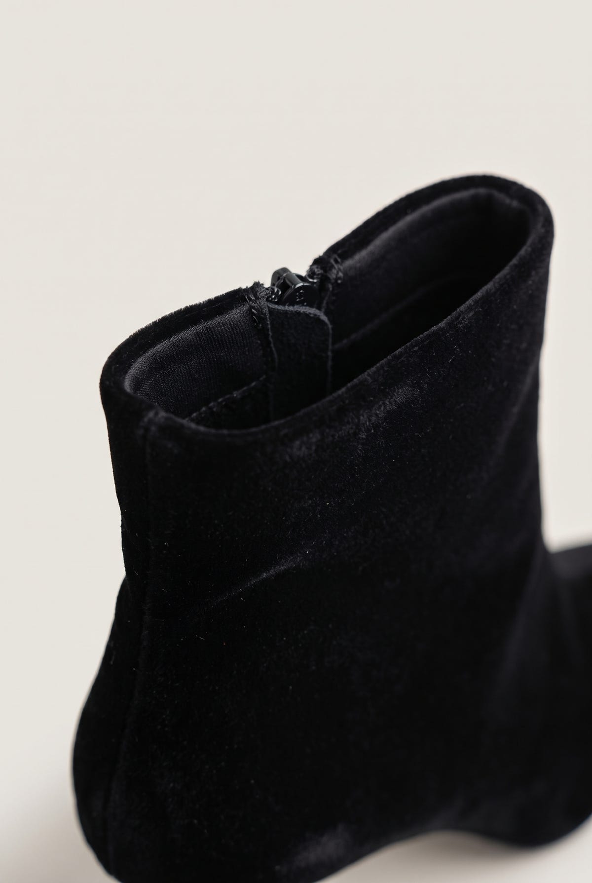 Close-up of black velvet ankle boot showing the soft pile texture and zip along the top edge of the shaft