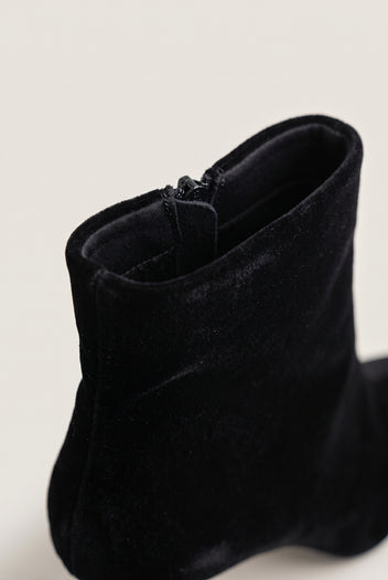 Close-up of black velvet ankle boot showing the soft pile texture and zip along the top edge of the shaft