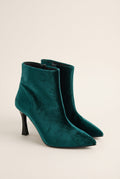 Pair of dark green velvet pointed toe ankle boots with stiletto heels in angled front view