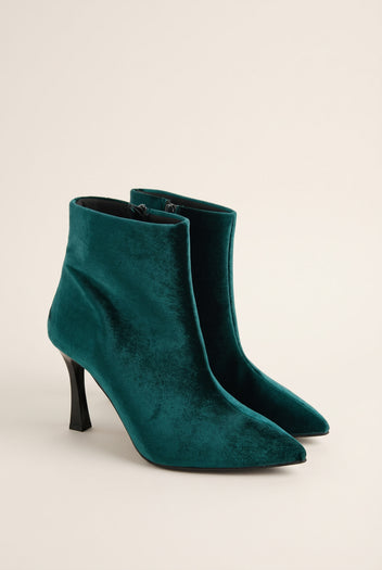 Pair of dark green velvet pointed toe ankle boots with stiletto heels in angled front view