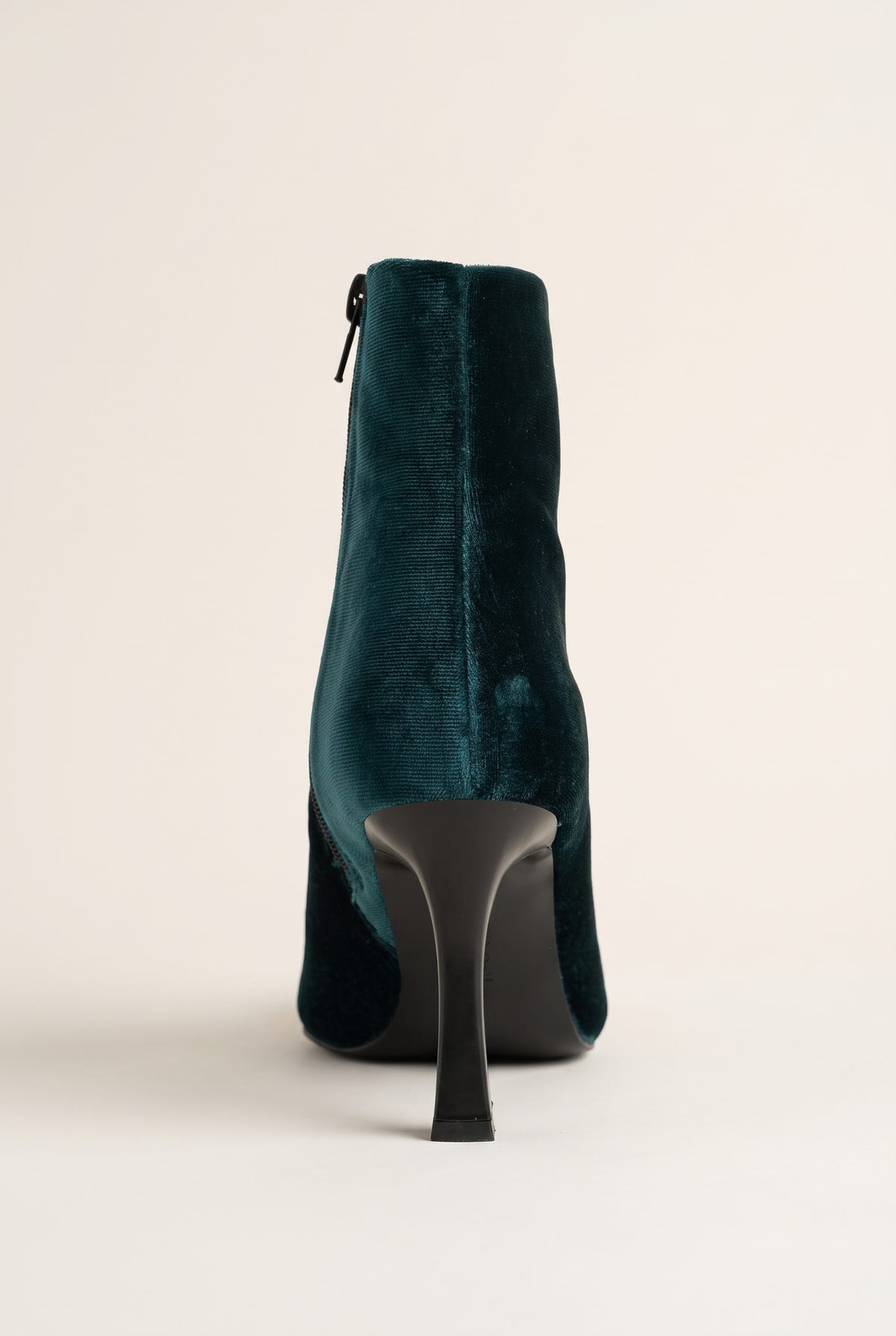 Back view of dark green velvet ankle boot showing the centered rear zip and tall stiletto heel