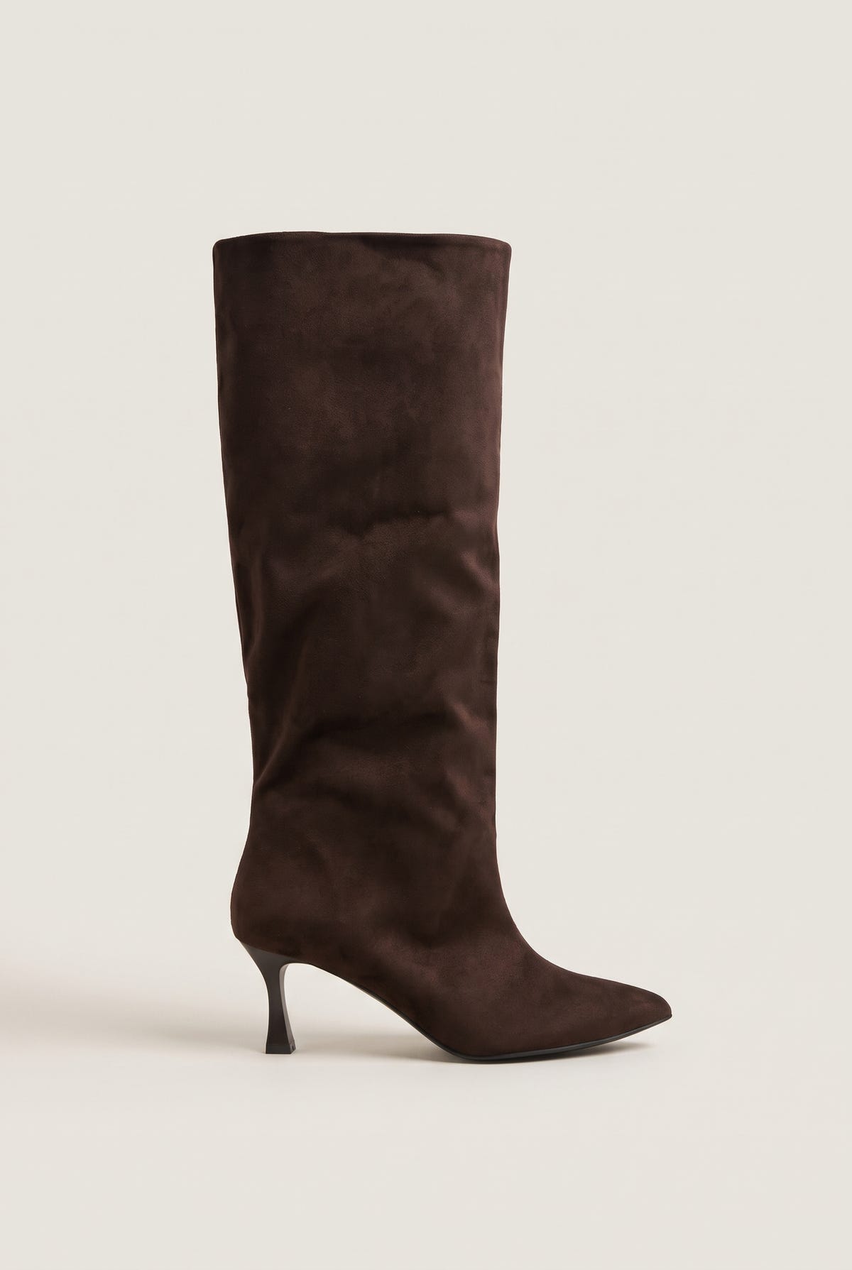 Pair of tall brown suede stiletto boots with pointed toes and slim mid height heel, side view on plain light setting