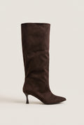Pair of tall brown suede stiletto boots with pointed toes and slim mid height heel, side view on plain light setting