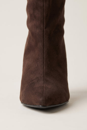 Close-up of brown suede stiletto boot toe and shaft showing soft suede texture and pointed tip with thin sole edge