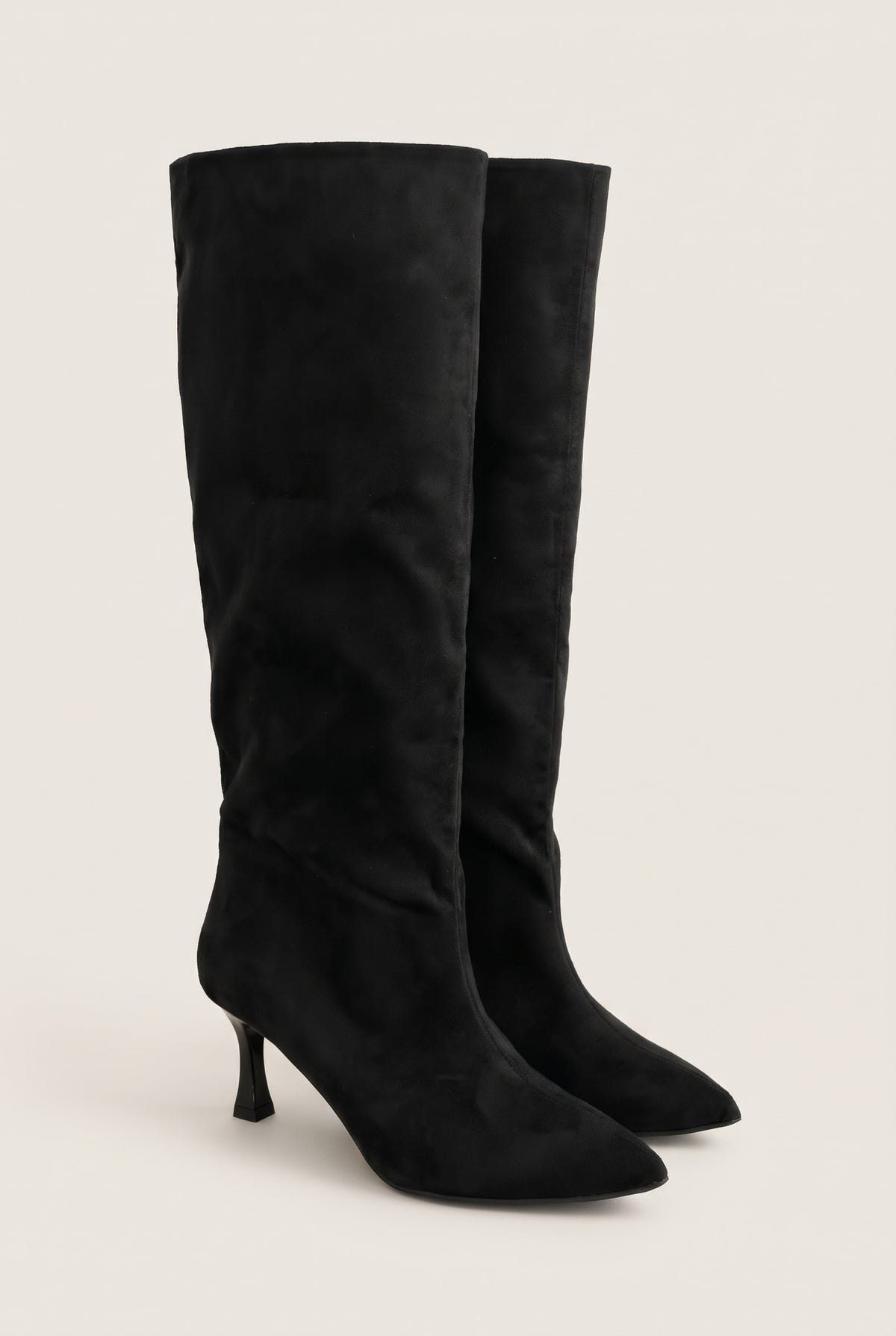 Pair of black suede knee high stiletto boots with pointed toes in angled front view