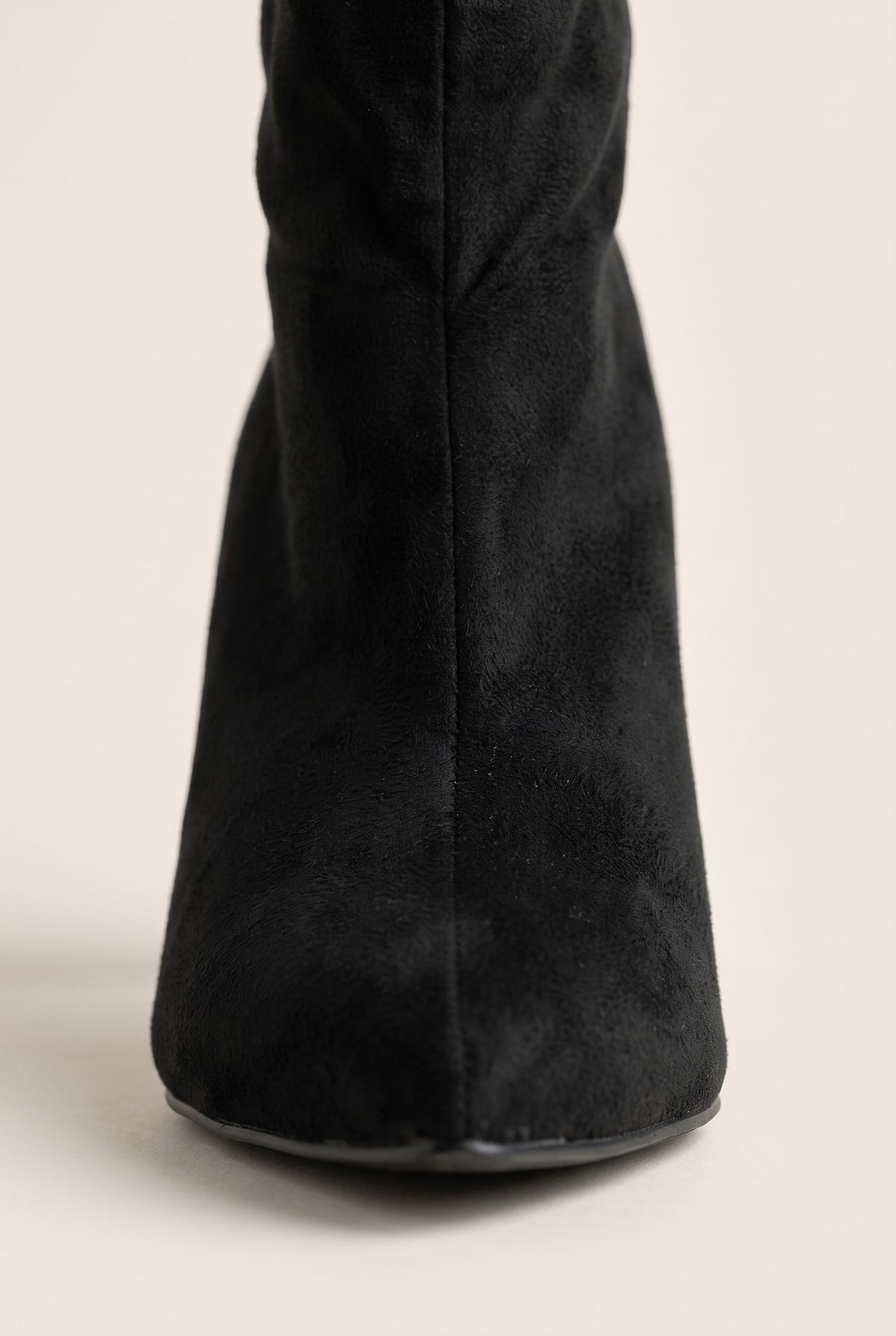 Close-up of black suede shaft and pointed toe tip showing the soft matte nap and slim stiletto heel