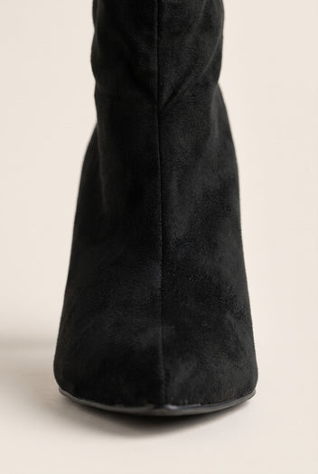 Close-up of black suede shaft and pointed toe tip showing the soft matte nap and slim stiletto heel
