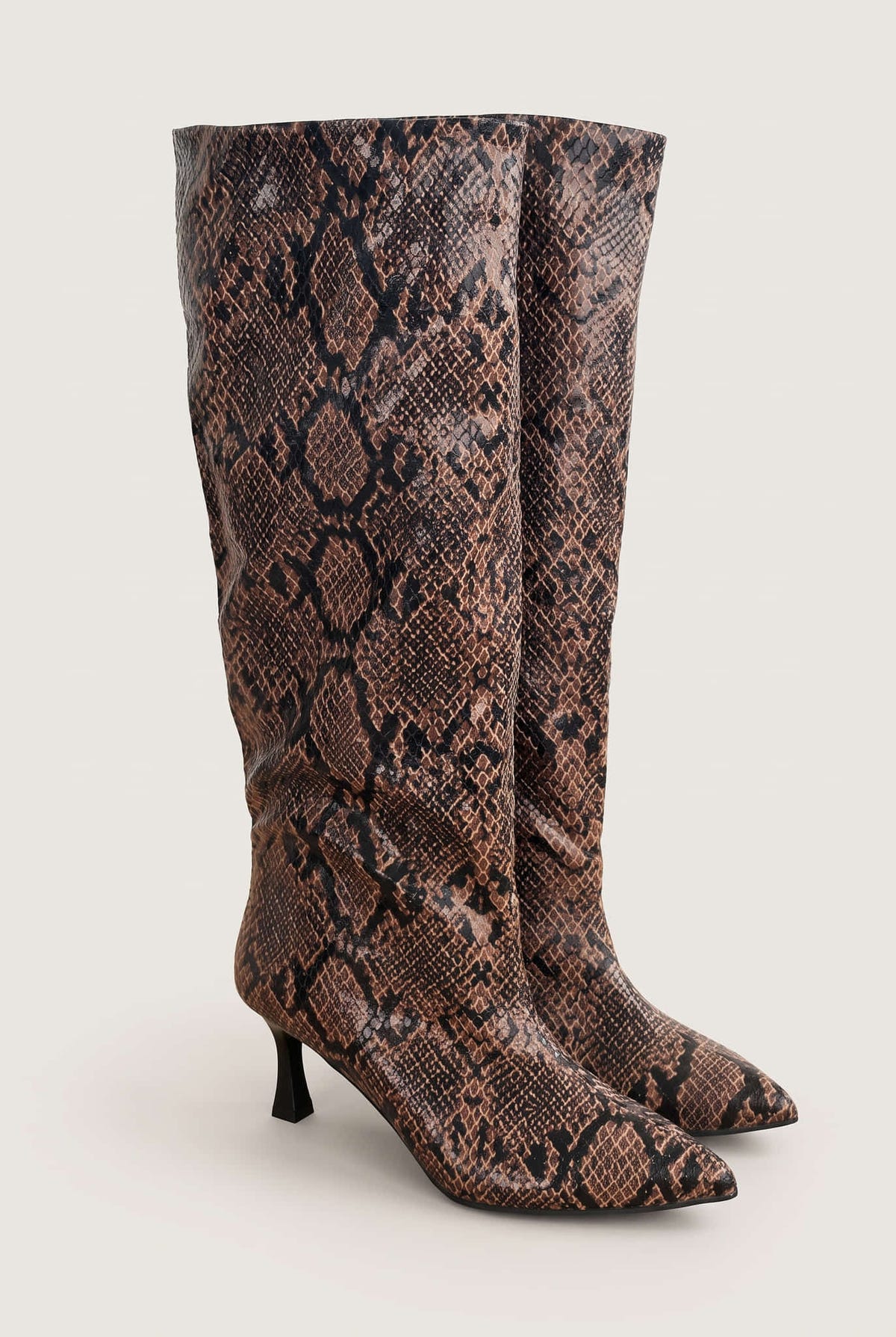Pair of brown snake print knee-high boots with pointed toes and slim heels, front three-quarter view