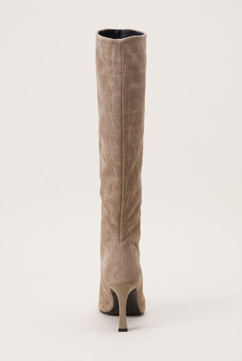 Back view of a knee-high beige suede boot showing the tall straight shaft and slim stiletto heel