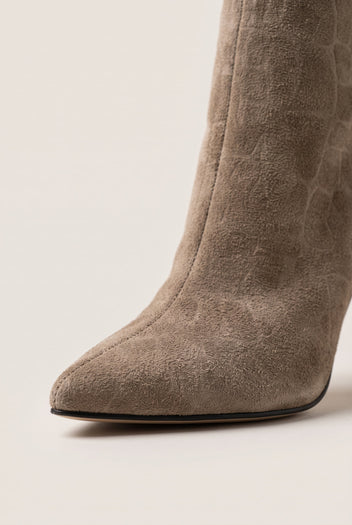 Close-up of a pointed toe and ankle on a beige croc-embossed suede boot with a sleek slim profile