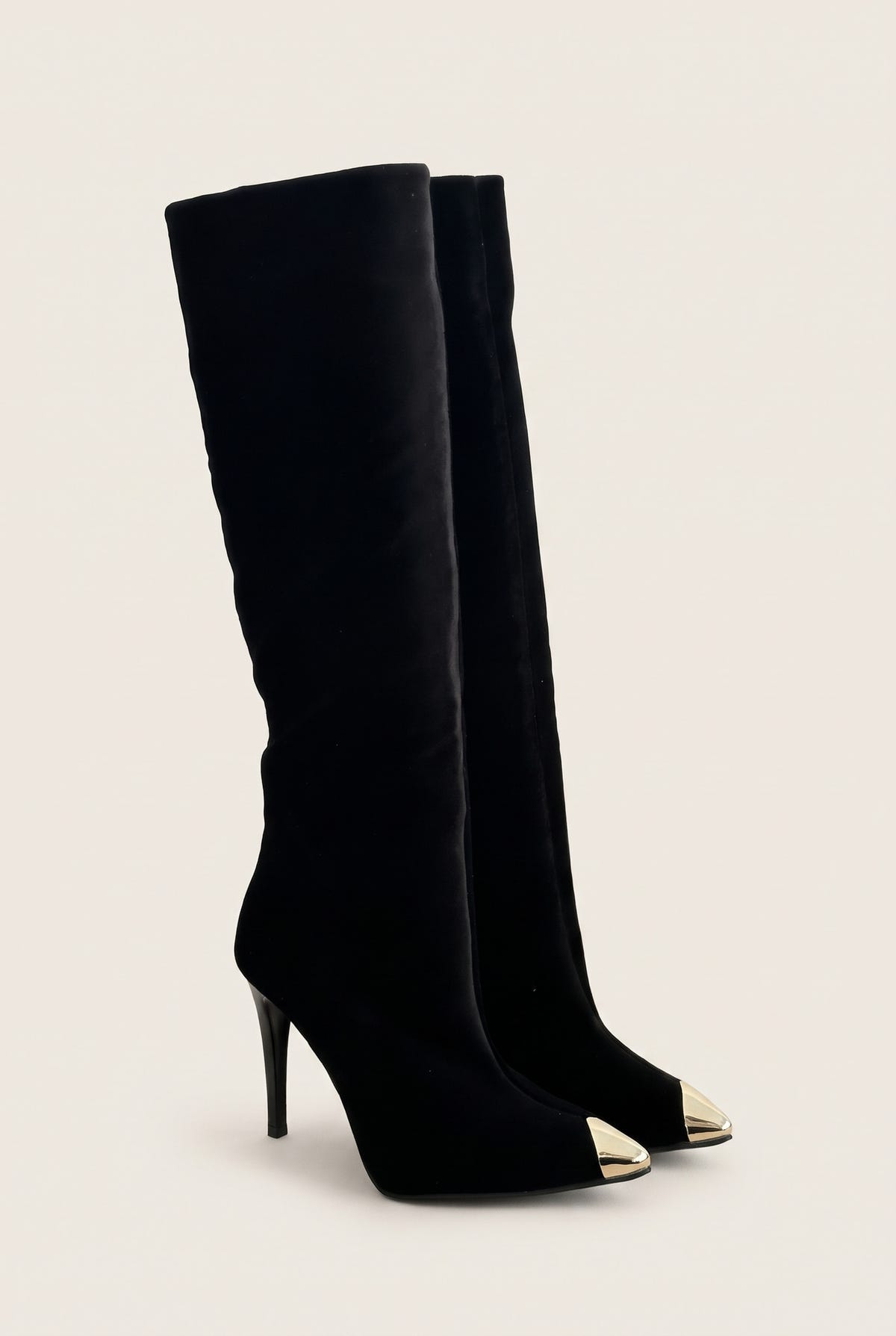 Pair of black velvet knee high boots with gold tone metal toe caps in angled front view