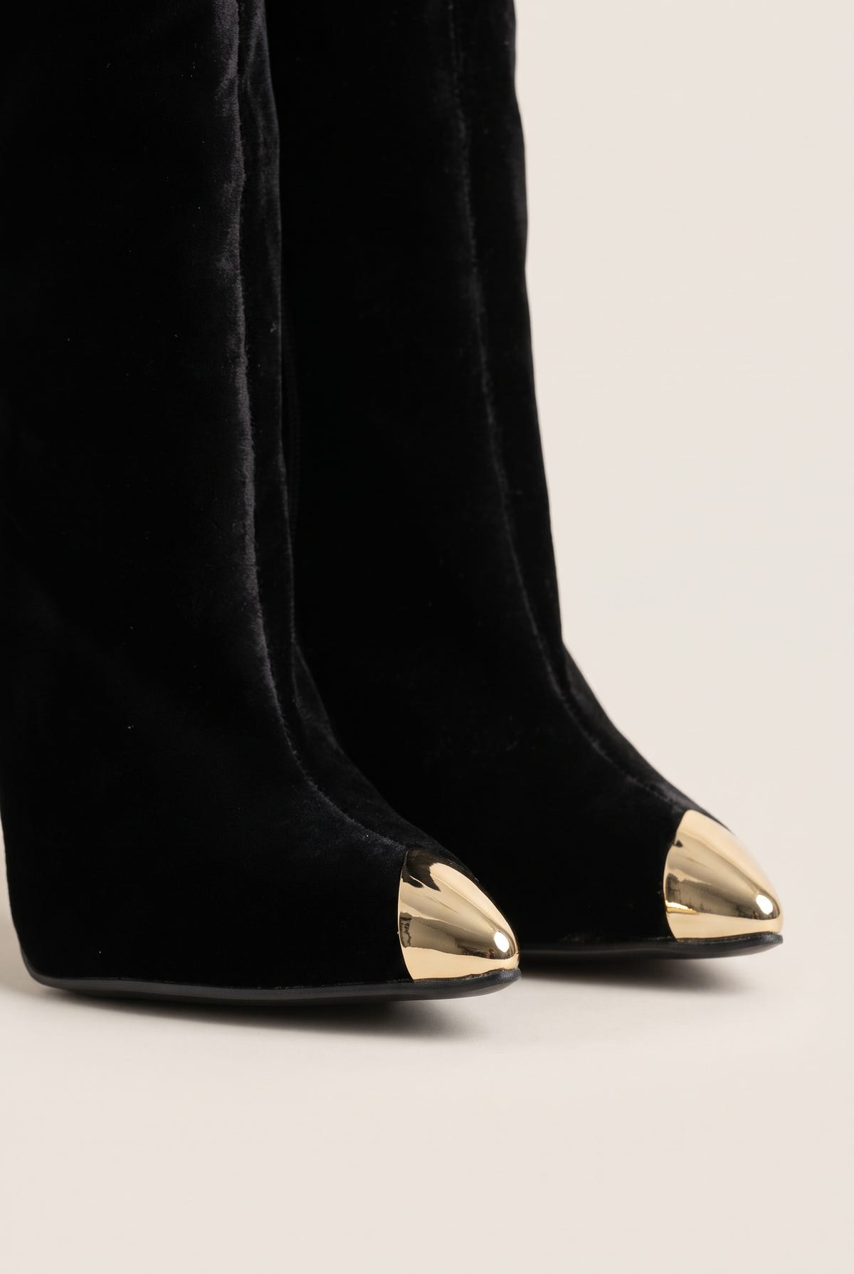 Close-up of black velvet boot tips showing the gold tone metal toe caps and soft pile texture