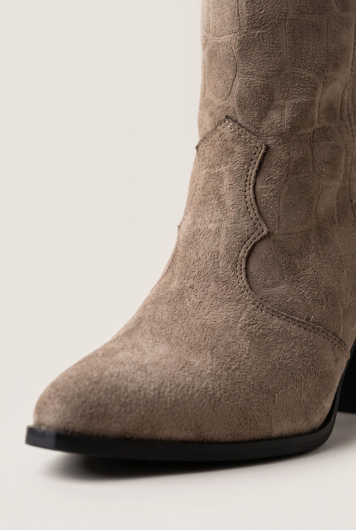 Close-up of beige suede cowboy boot showing croc embossed texture, stitched shaft panel and pointed toe