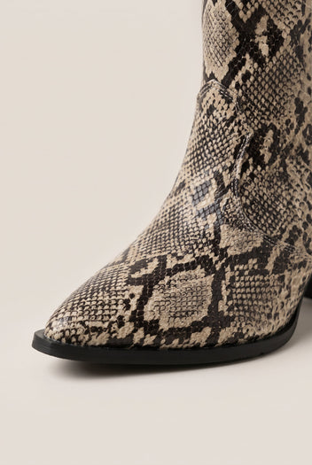 Close-up of ivory and black snake print cowboy boot showing pointed toe and stacked heel detail