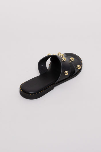 Black leather studded slide sandals with gold studs, angled view on grey background