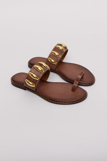 Brown leather toe-ring sandals with gold studs, angled view on grey background in studio light