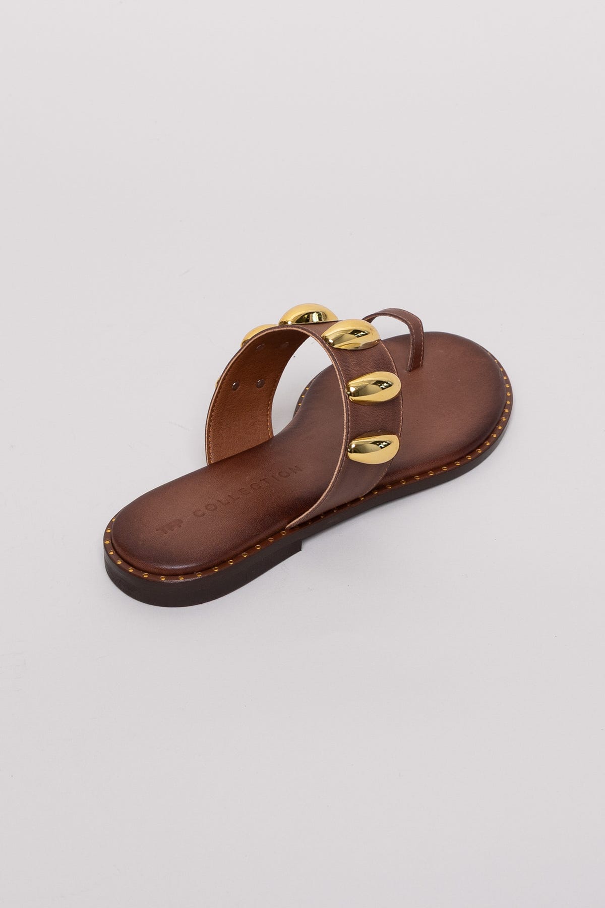 Brown leather toe-ring sandal with gold studs, angled view on grey background in studio light