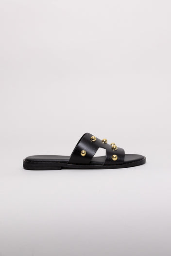 Black leather slide sandal with gold stud detail and flat sole, angled view on a white background