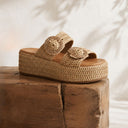 Woven sandals on a wooden block with a neutral background