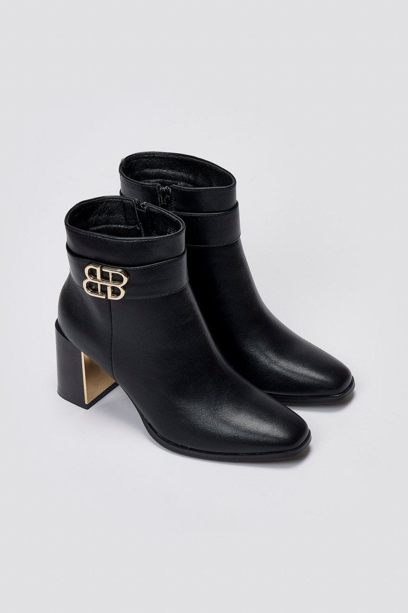 Black leather ankle boots with pointed toe, block heel and gold-tone logo buckle, pair in angled view on a light grey background