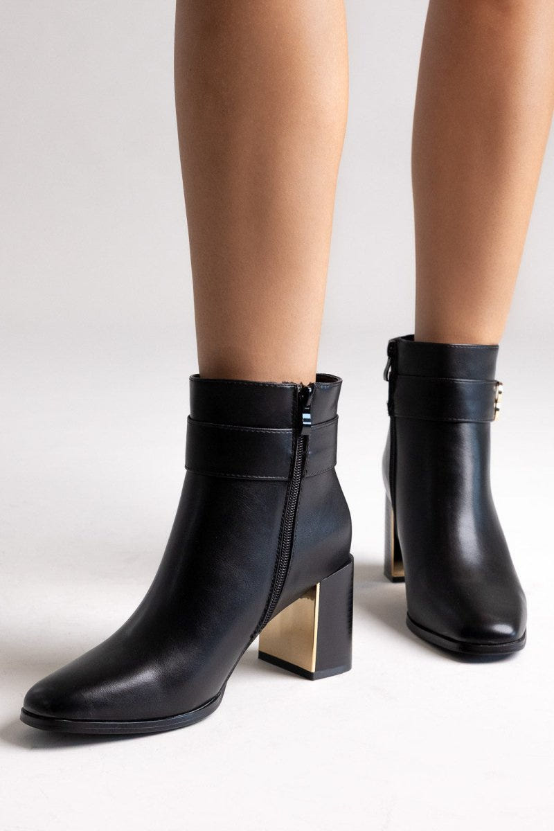 Black leather ankle boots with block heel, gold-tone logo buckle and gold-tone heel detail, pair in angled view on a light grey background