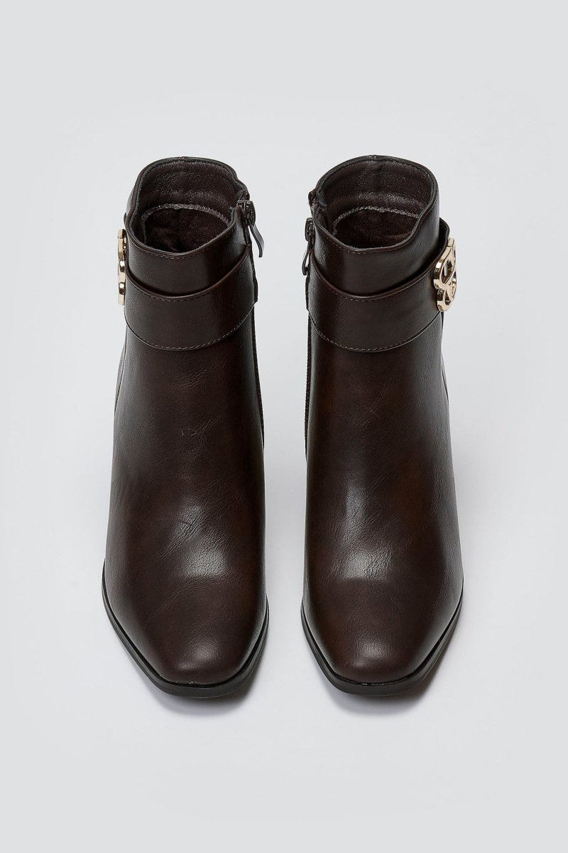 Dark brown leather ankle boots with block heel and gold-tone logo buckle, pair in top-down view on a light grey background