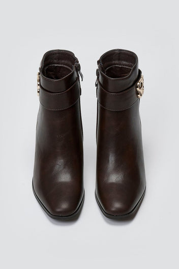 Dark brown leather ankle boots with block heel and gold-tone logo buckle, pair in top-down view on a light grey background