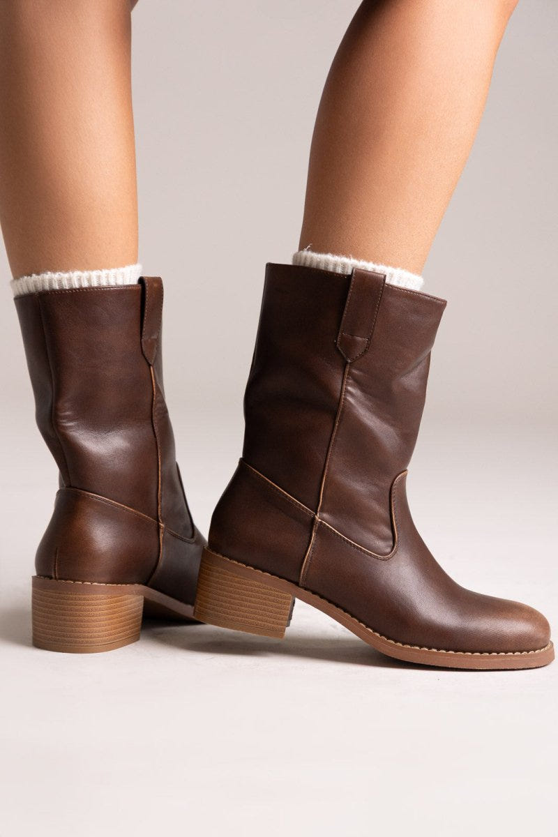 Brown leather mid-calf boots with block heel and side panel, pair in angled view on a model's legs in studio light