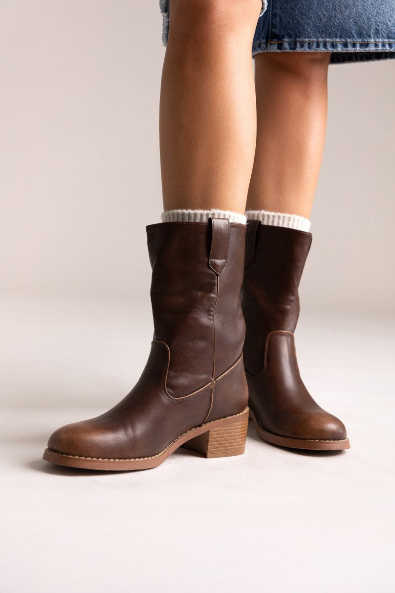 Dark brown leather mid-calf boots with block heel and croc-embossed detail, pair in angled view on a model's legs in studio light