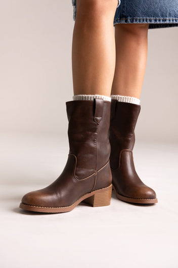Dark brown leather mid-calf boots with block heel and croc-embossed detail, pair in angled view on a model's legs in studio light
