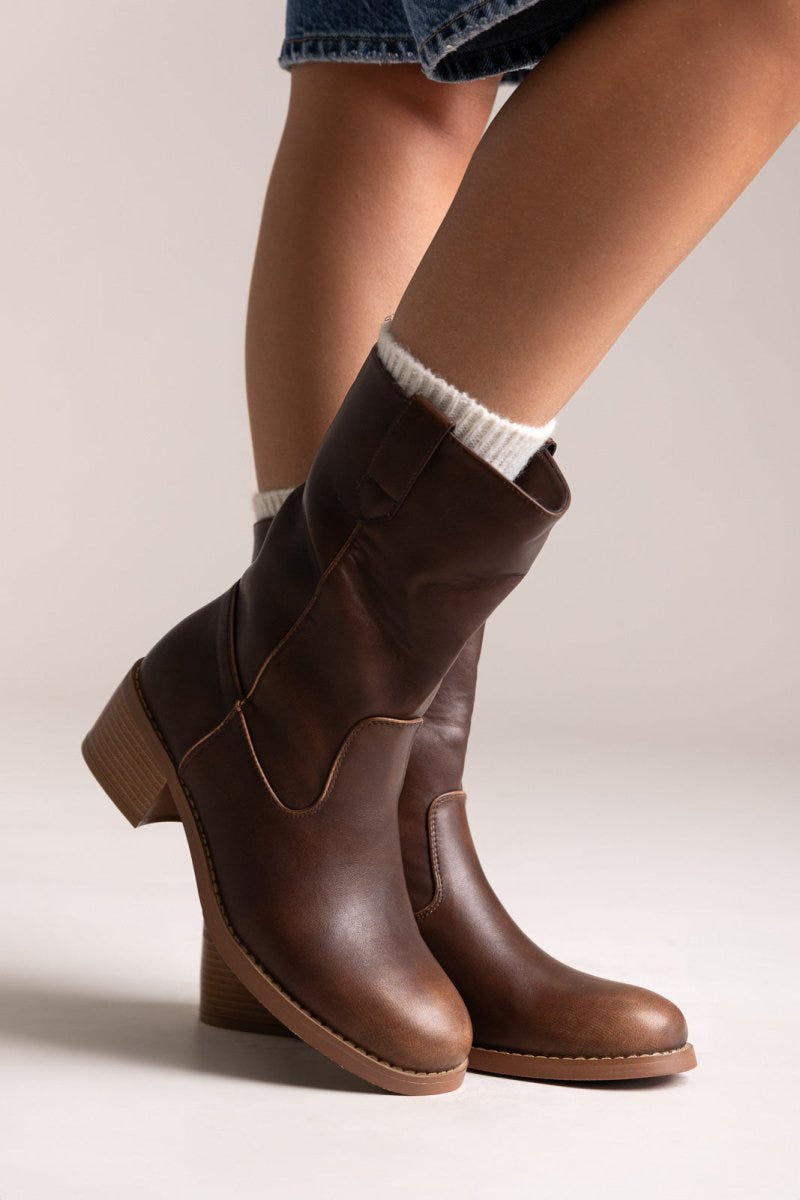 Brown leather mid-calf boots with block heel and elastic side panel, pair in angled view on a model's legs in studio light