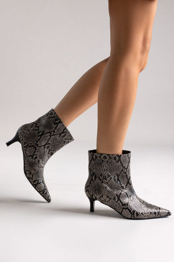 Grey snake-embossed leather ankle boots with pointed toe and kitten heel, pair in side view on a model's legs in studio light
