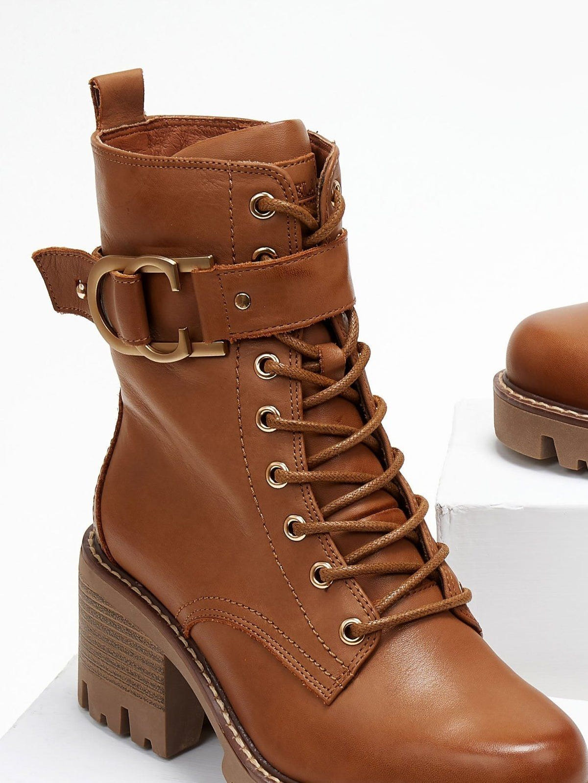 Tan leather lace-up ankle boot with block heel and buckle straps, close view on a white background