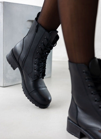 Black leather lace-up ankle boot with block heel, close view on a model's legs and sheer black tights