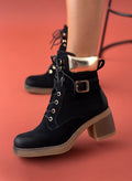 Black lace-up ankle boot with gold padded collar, buckle strap and chunky block heel, worn on model, side view