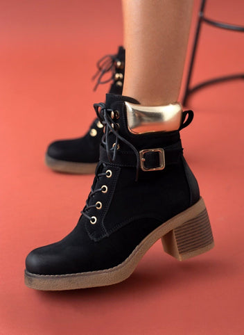 Black lace-up ankle boot with gold padded collar, buckle strap and chunky block heel, worn on model, side view
