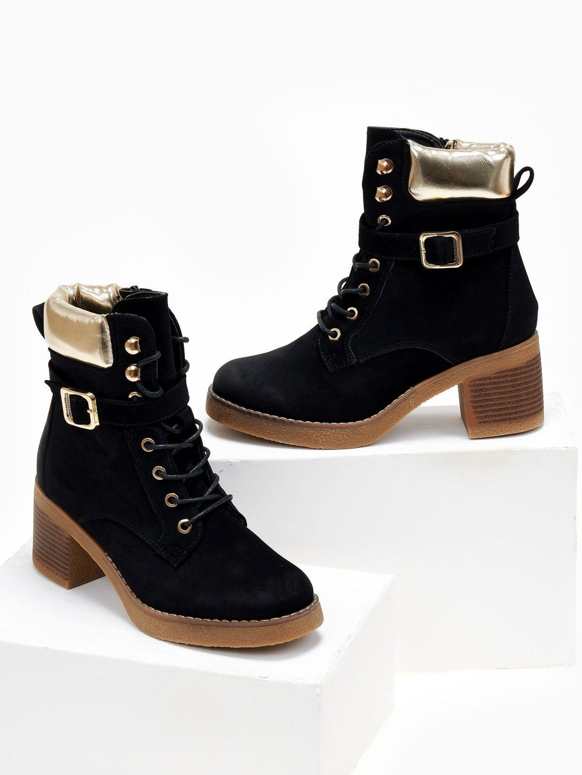 Black lace-up block heel ankle boots with gold padded collar, buckle strap and gum sole, front view on white blocks