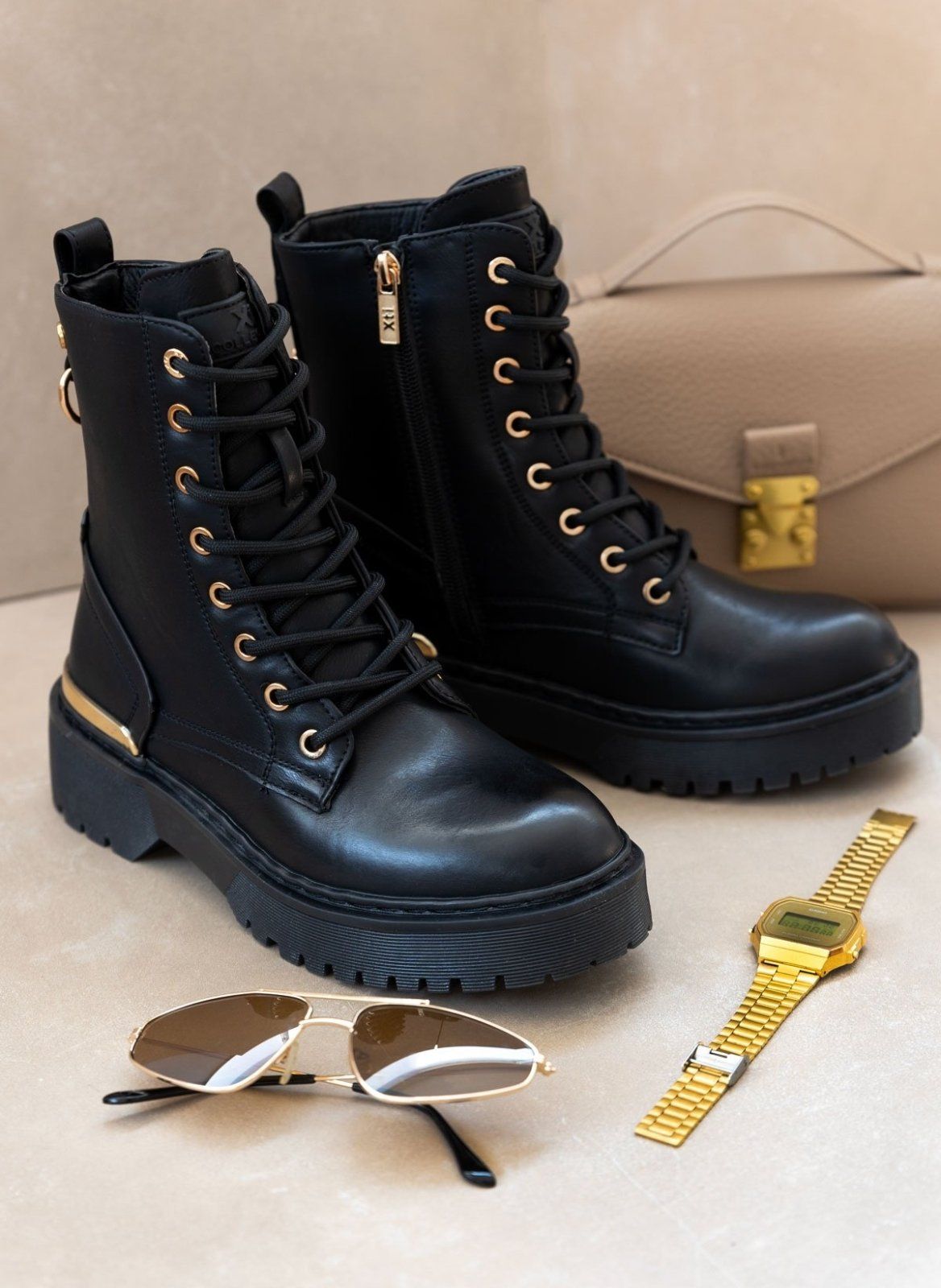 Black lace-up boots with gold eyelets and chunky sole, styled with sunglasses, watch and handbag
