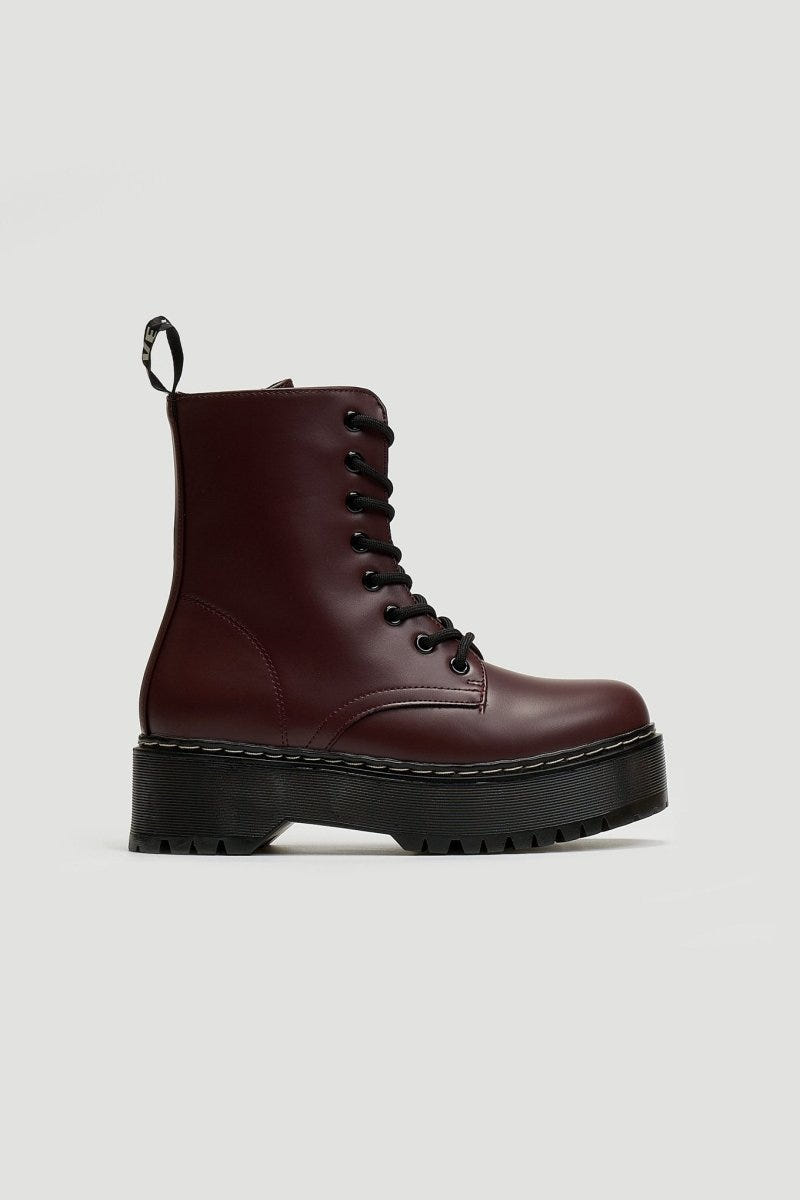 Single burgundy leather lace-up boot with chunky black sole and pull tab, side view on grey background