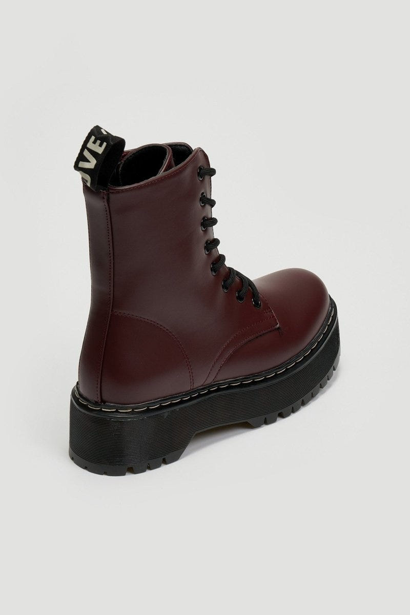 Burgundy leather lace-up boot with chunky black platform sole and pull tab, side view on grey background