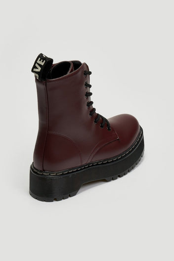Burgundy leather lace-up boot with chunky black platform sole and pull tab, side view on grey background