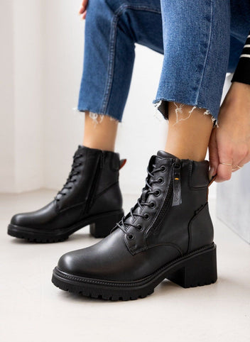 Model wearing black leather ankle boots with block heel and zip detail, styled with blue jeans