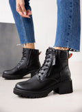 Model wearing black lace-up ankle boots with block heel and chunky sole, styled with blue jeans